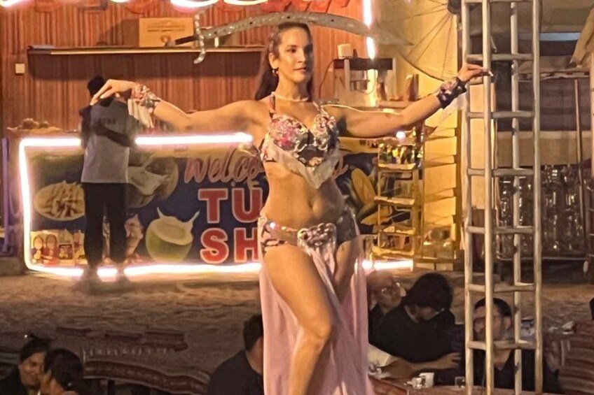 Une personne qui fait une performance devant un panneau indiquant : « Bienvenue à TUSHA ». 3