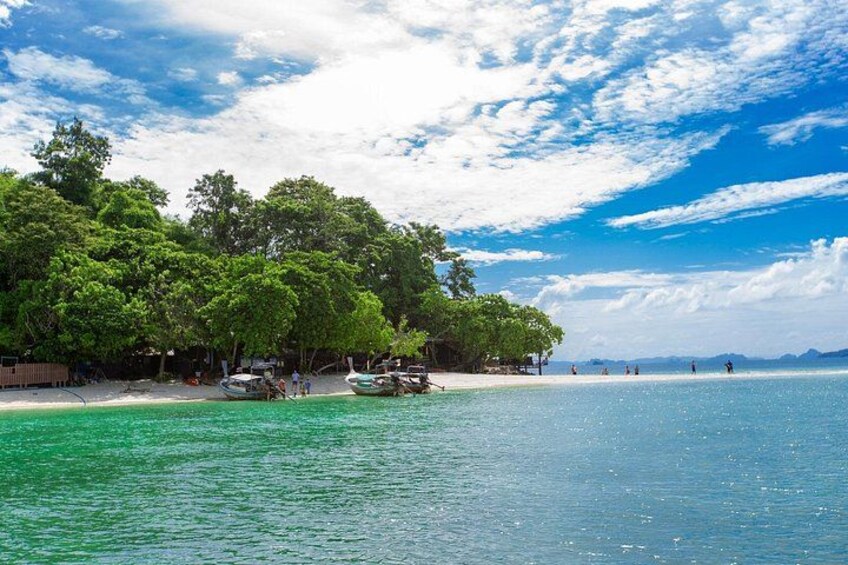 A beach with clear turquoise water, a sandy shore, and lush green trees. 4