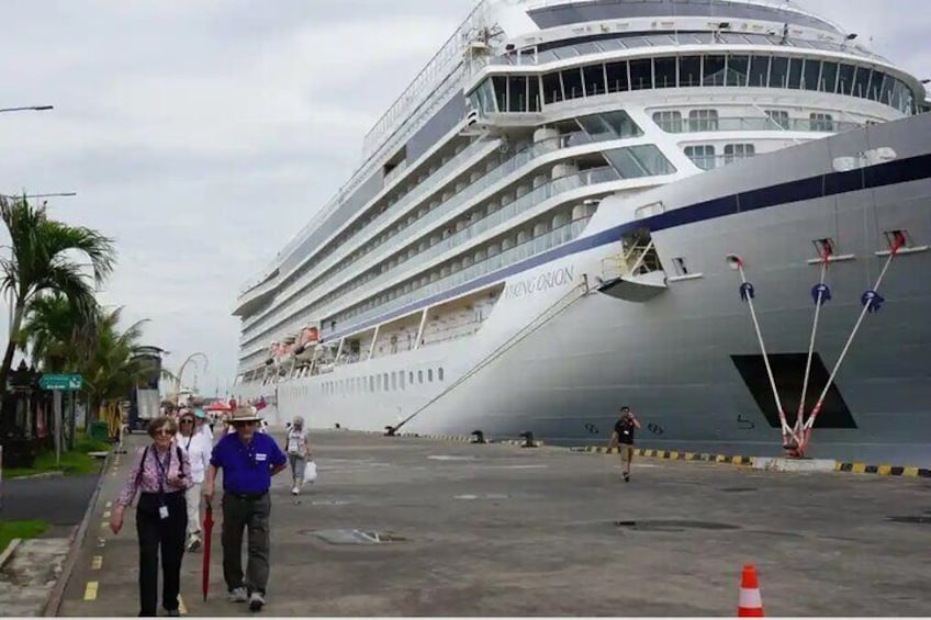 Un gran crucero amarrado en un puerto, con gente caminando alrededor. 2