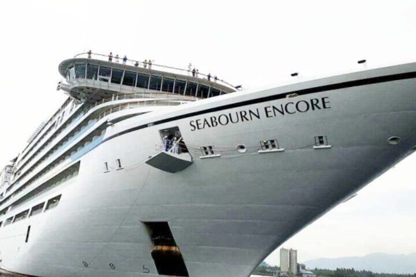 Un gran crucero llamado 'SEABOURN ENCORE' con múltiples cubiertas y pasajeros visibles en la cubierta superior. 3