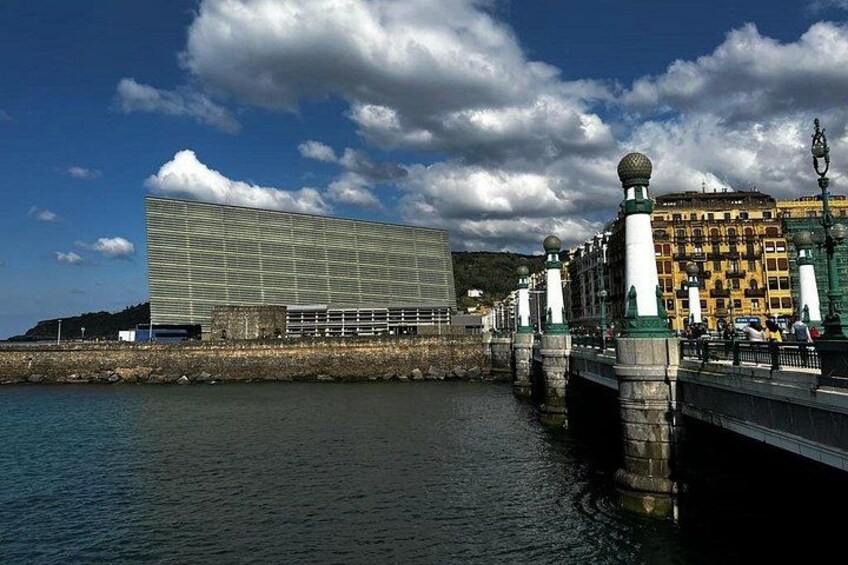 A modern building, a bridge, and historic buildings by a waterfront. 2