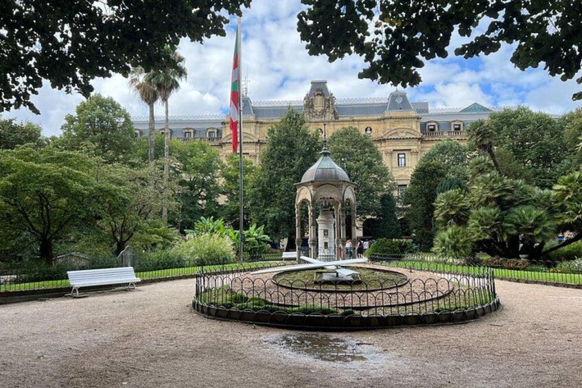 A park with a gazebo, fountain, and flagpole. 3