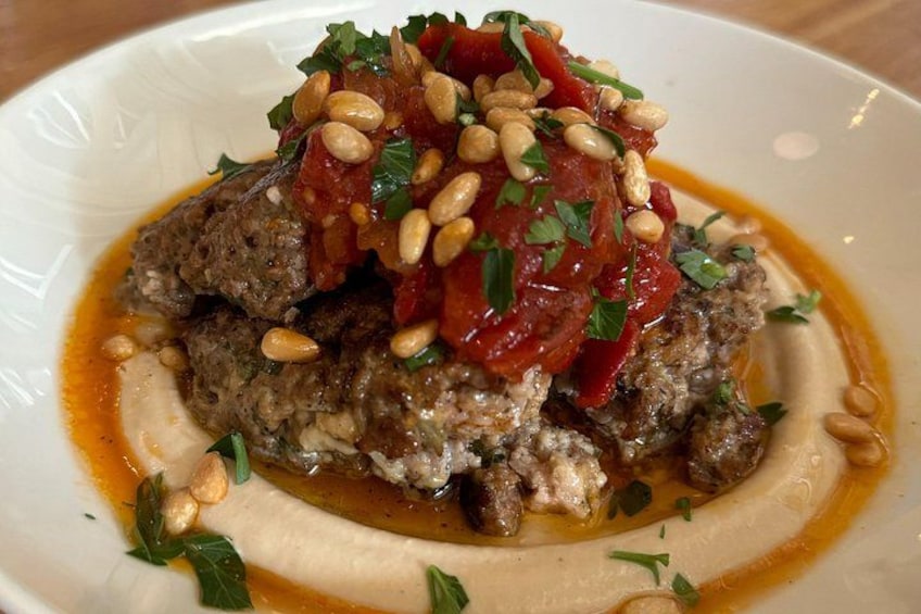 Een bord eten met gehaktballetjes, tomatensaus, pijnboompitten en kruiden. 2