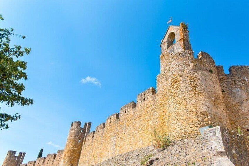 A stone castle with multiple towers and battlements under a clear blue sky. 5