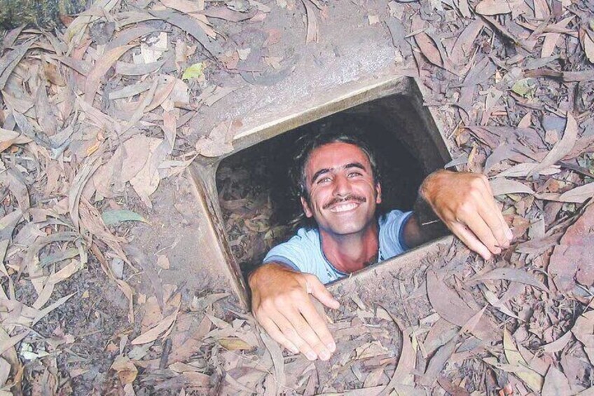 A person peeking out of a hole in the ground surrounded by dry leaves. 3
