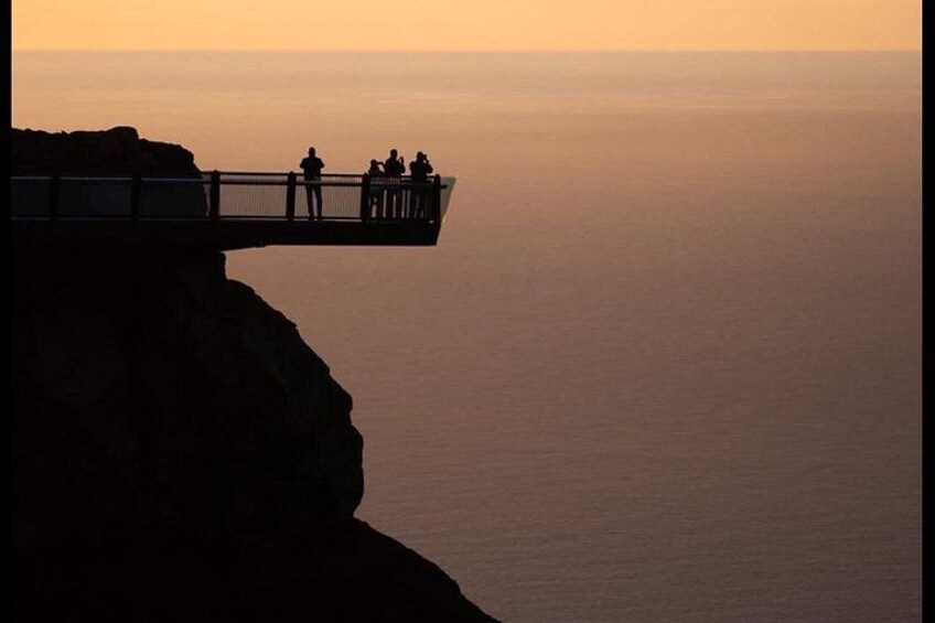 A cliffside overlook with a viewing platform and people. 5