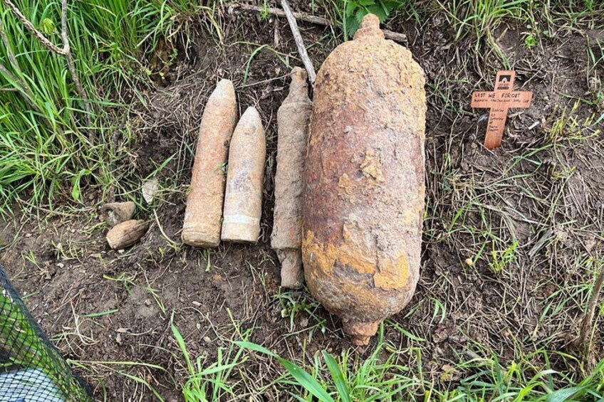 En stor, rostig bomb, tre mindre bomber och ett kors på marken. 2