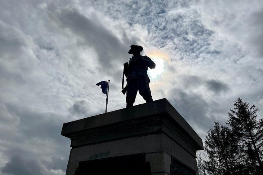 En staty av en soldat på en piedestal, med en flagga, mot en bakgrund av en molnig himmel. 5