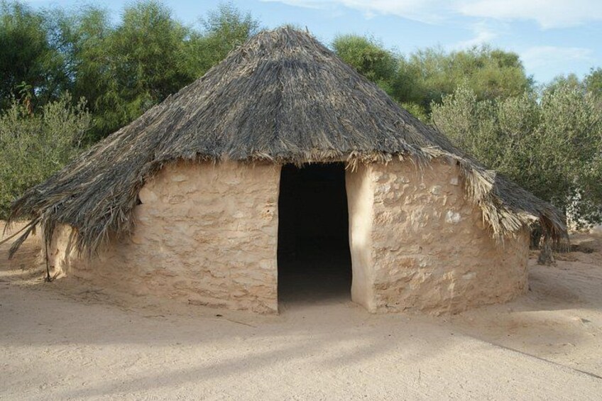 A traditional thatched hut with a dirt ground. 3