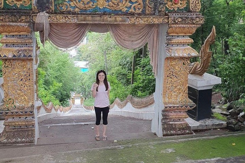 A person standing in front of an ornate gate with intricate designs and a statue on the right. 4