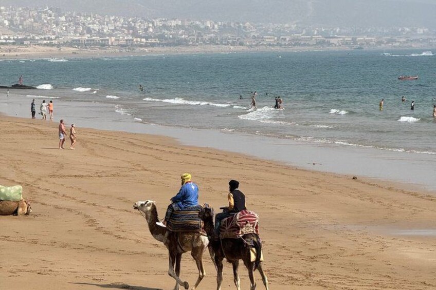 Een strand met mensen die wandelen en kameelrijden. 4