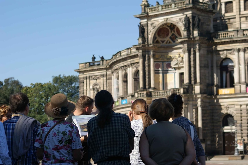 A group of people standing in front of a historic building with ornate architecture. 5