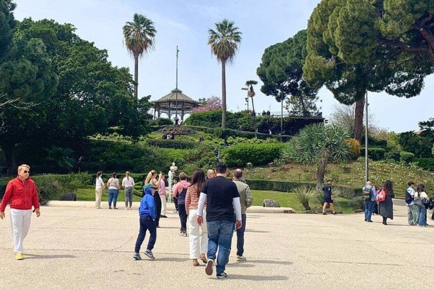 A park with people walking, palm trees, and a gazebo. 2
