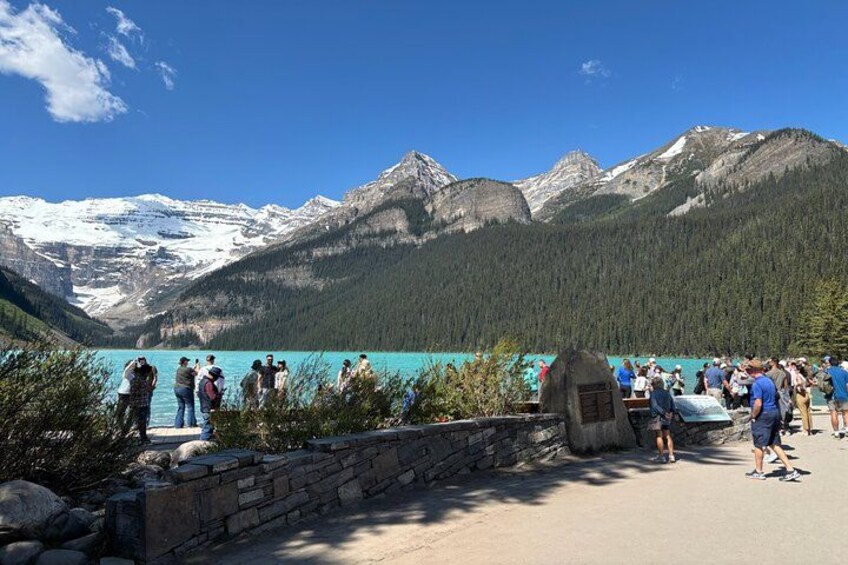Un gruppo di persone in un punto panoramico sul lago, con montagne sullo sfondo. 2