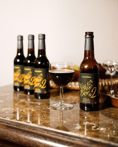Four bottles of Kamado Bier No. 2 and one glass of beer on a marble countertop. 5