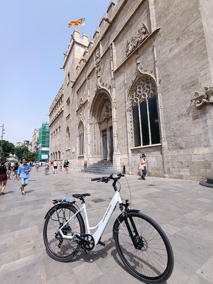 A white bicycle parked in front of a historic building with ornate architecture. 4
