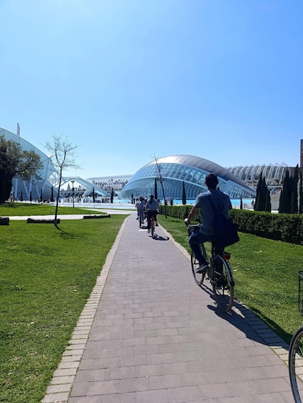 A pathway with cyclists and pedestrians, surrounded by green grass and modern architecture. 5
