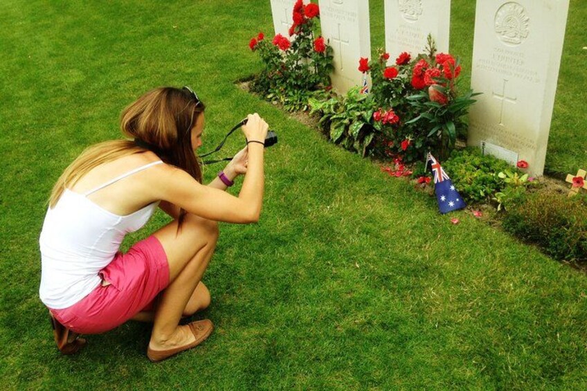A person kneeling by a grave with flowers and a flag. 2