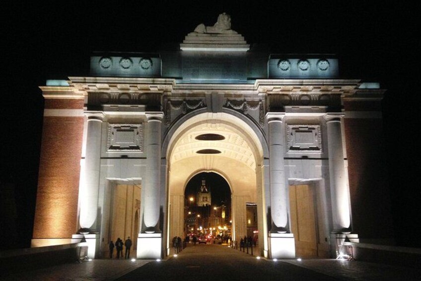 A grand, illuminated archway at night with a central dome and flanking columns. 2