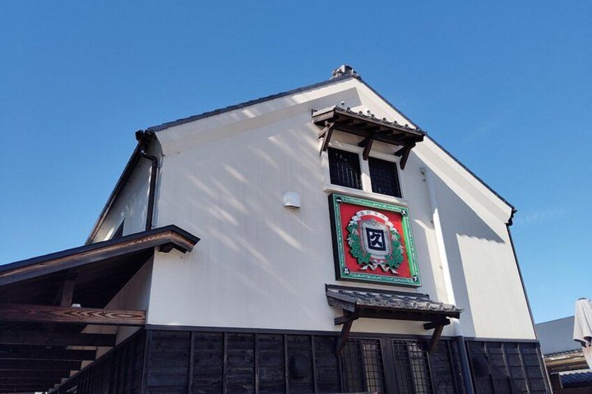 A building with a white facade, a green-framed clock, and a wooden staircase. 2
