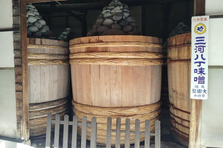 Large wooden barrels stacked in a warehouse with a wooden fence in front. 5