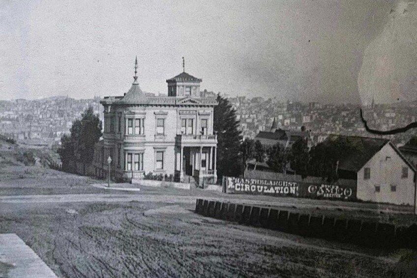 Un bâtiment historique doté d’une tour imposante, entouré d’un champ et d’un panneau publicitaire faisant la promotion d’un hôpital. 4