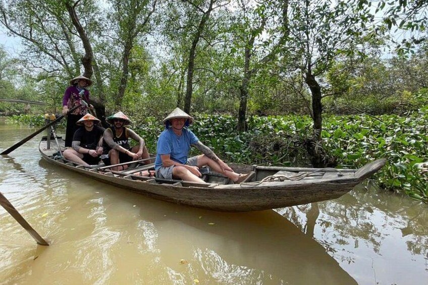 Un bateau en bois, avec des personnes portant des chapeaux, flotte sur une rivière bordée de verdure. 4