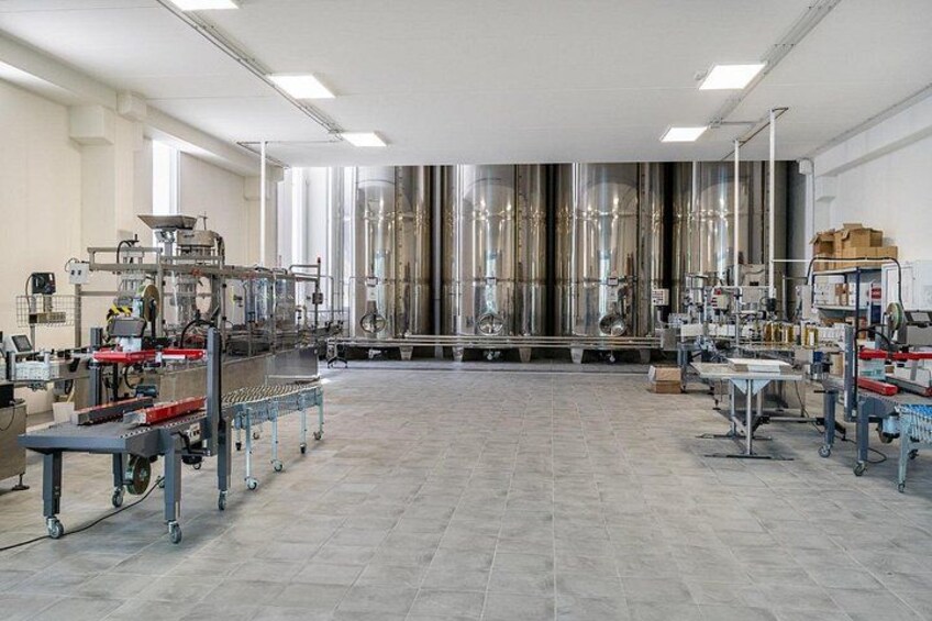 Een nette, industriële laboratoriumruimte met roestvrijstalen apparatuur, een centraal werkblad en een betegelde vloer. 2