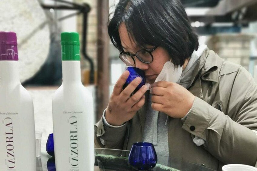 Een persoon zit aan een tafel met flessen met de naam 'Cozorla' en een blauw glas. 4