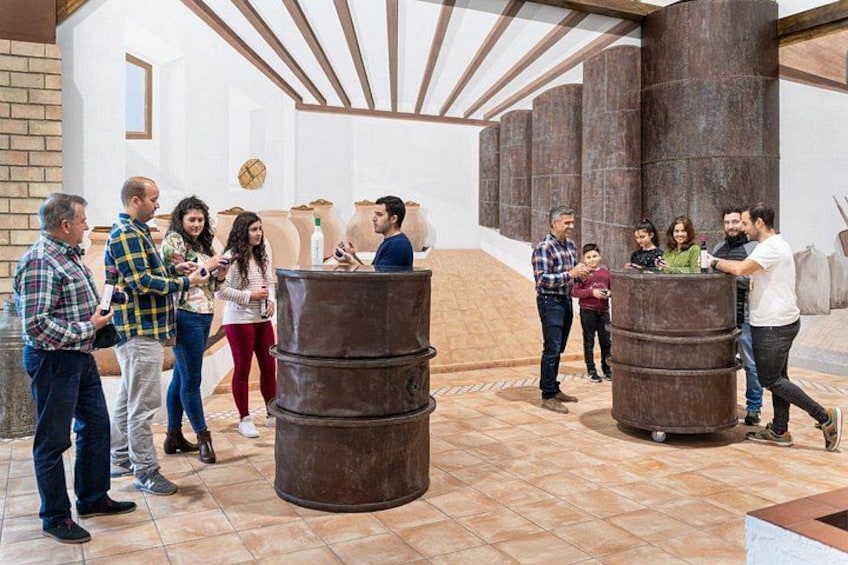 Een groep mensen in een ruimte met grote, cilindervormige objecten en een aflopende vloer. 3