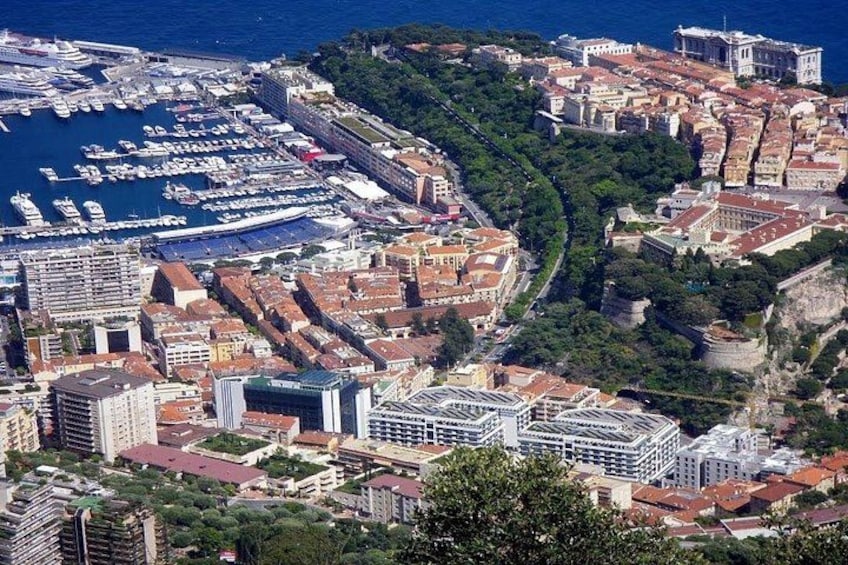 Una ciudad costera con un puerto deportivo, edificios urbanos densos y un paisaje montañoso al fondo. 3
