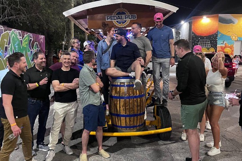 A group of people around a barrel with a sign that reads 'PEDAL PUB.' 2