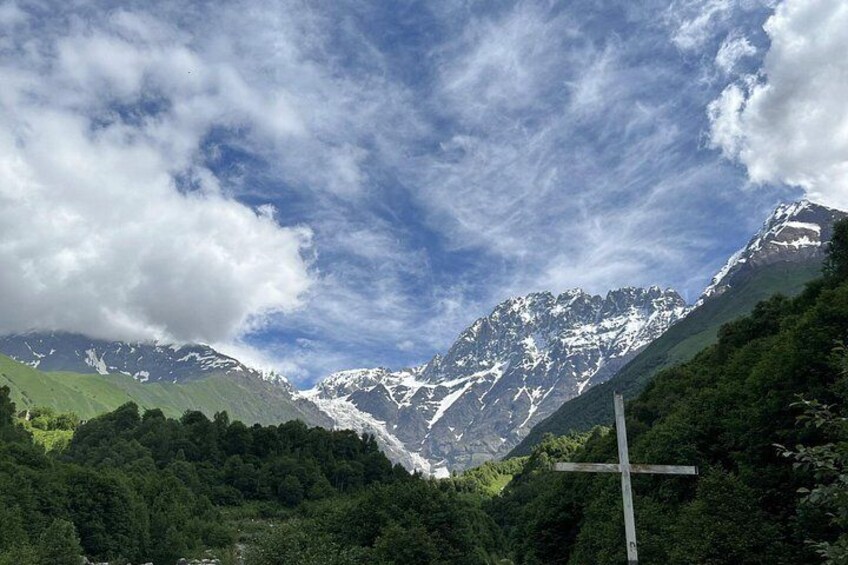 A mountain landscape with a cross in the foreground. 4
