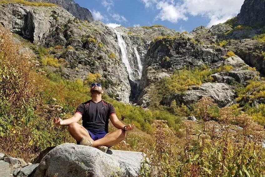A person meditating on a rock with a waterfall in the background. 5