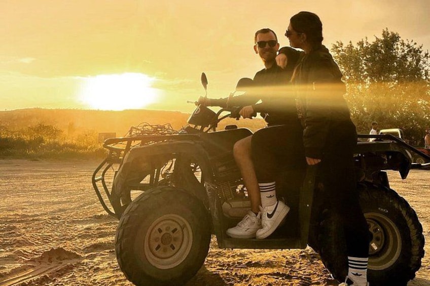 Zwei Personen fahren mit einem Quad, im Hintergrund ein Sonnenuntergang. 4