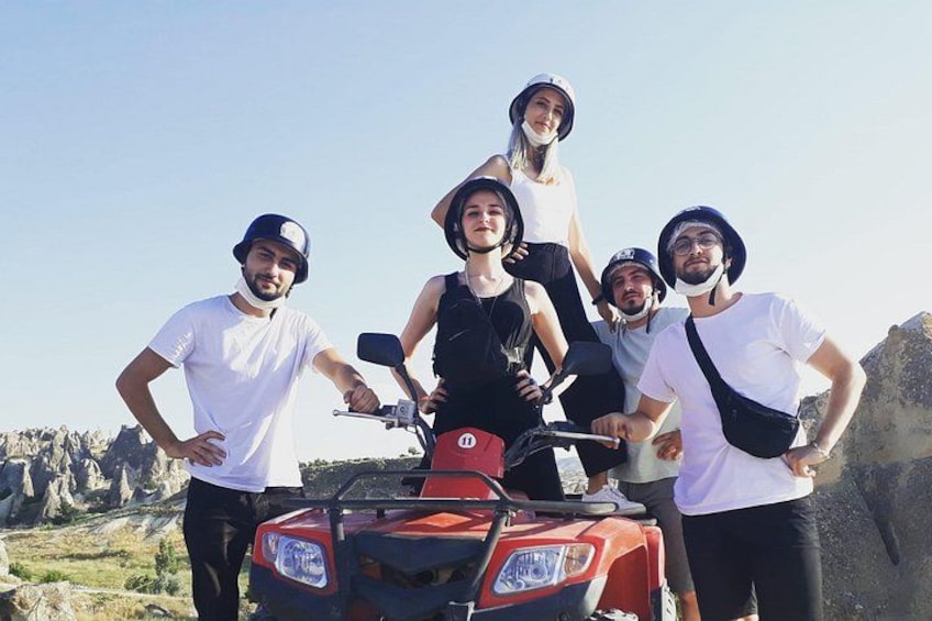 Eine Gruppe von Menschen steht um ein rotes Geländefahrzeug in einer felsigen Outdoor-Umgebung. 2