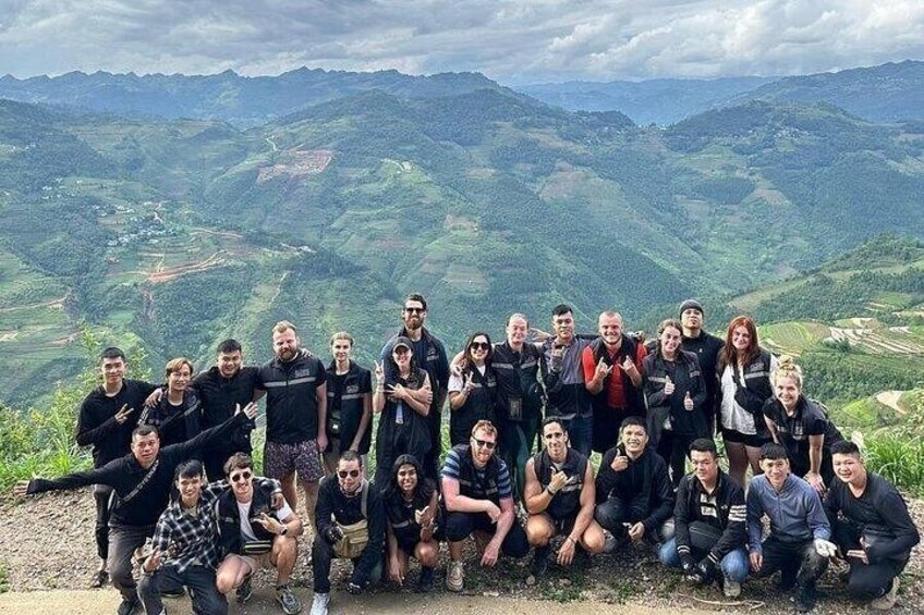 A group of people posing on a hilltop with a mountainous landscape in the background. 5