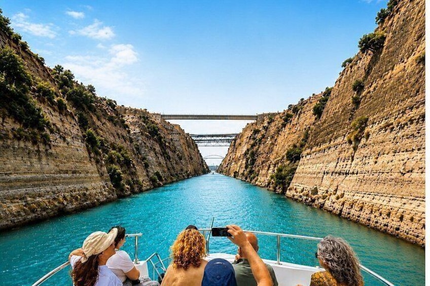 A boat on a narrow waterway flanked by steep cliffs, with a bridge in the distance. 1