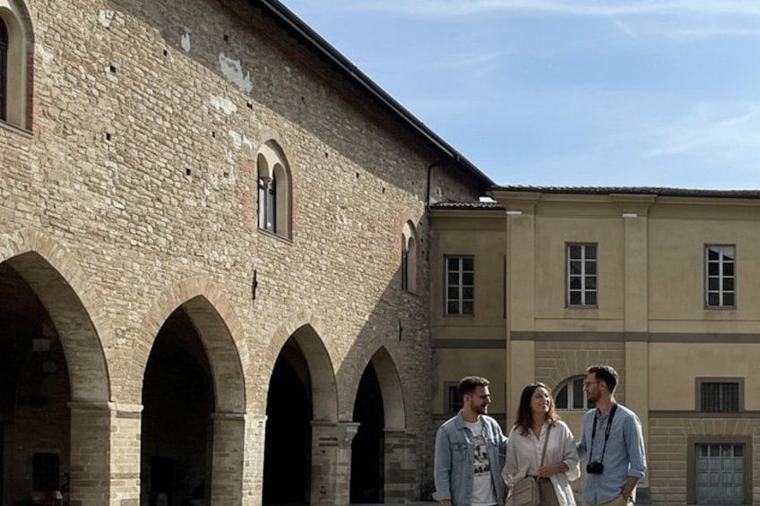 A historic building with arched walkways and a group of people standing in front. 2