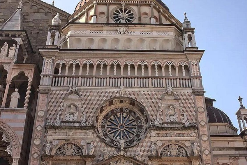 A historic building with intricate stonework, a large circular window, and a dome. 3