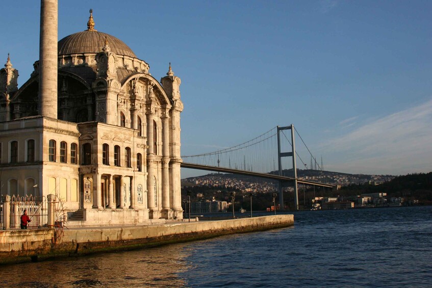 A historic building with a large dome and columns, a bridge in the background, and a body of water in the foreground. 4