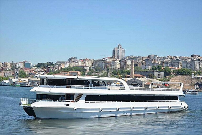 A large white boat on water with a cityscape in the background. 1