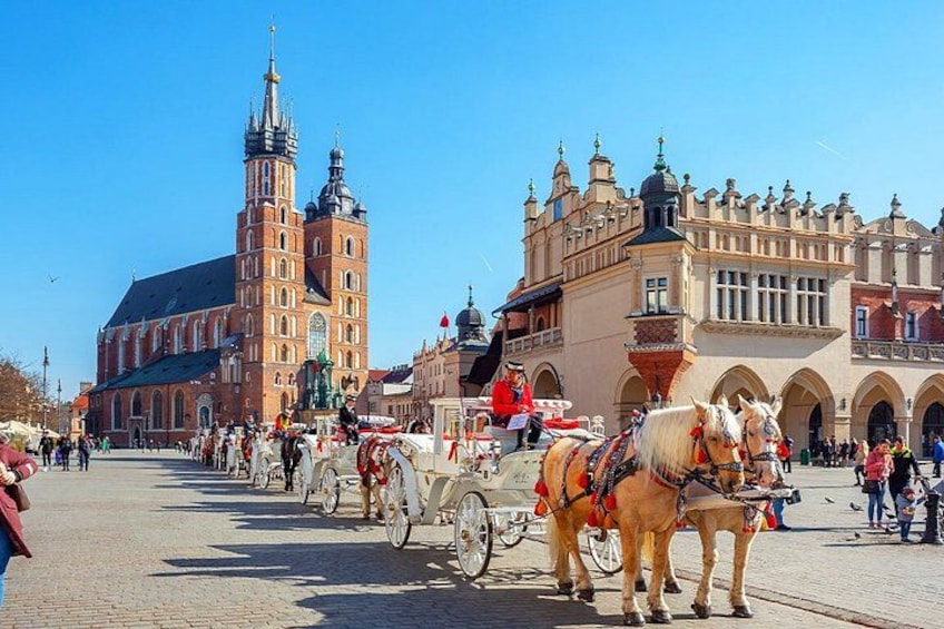 A historic square with horse-drawn carriages, a prominent church, and ornate buildings. 1