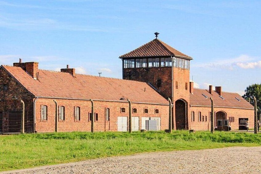 A brick building with a tower, a gravel path, and green grass. 3