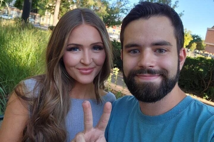 Two people outdoors with greenery in the background. 5