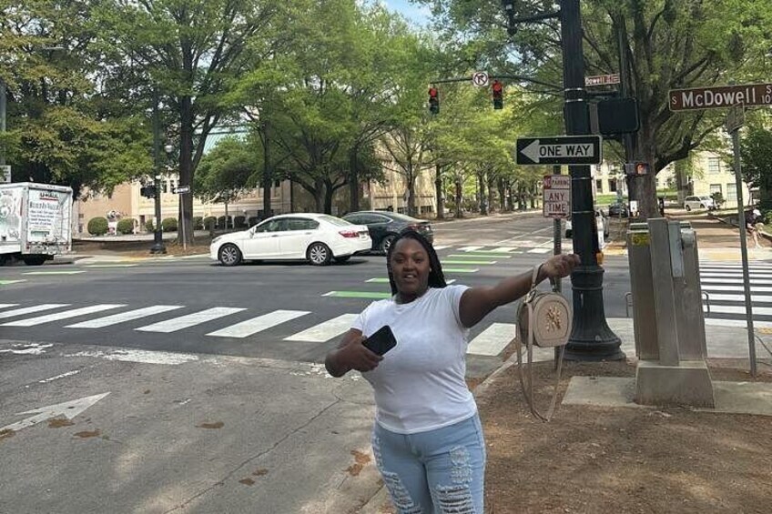 A person standing at a crosswalk with traffic lights and street signs. 2
