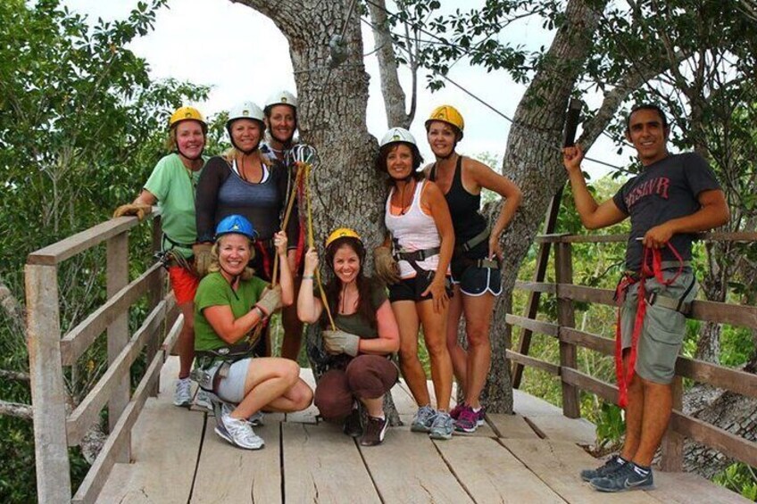 A group of people on a wooden bridge with trees in the background. 2