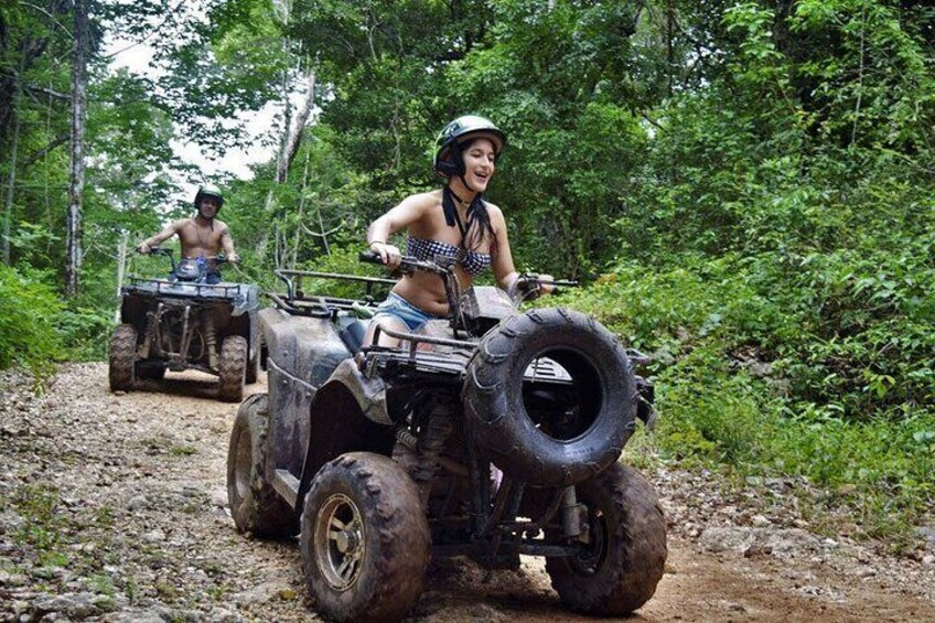 Two people riding ATVs on a dirt path in a forested area. 5