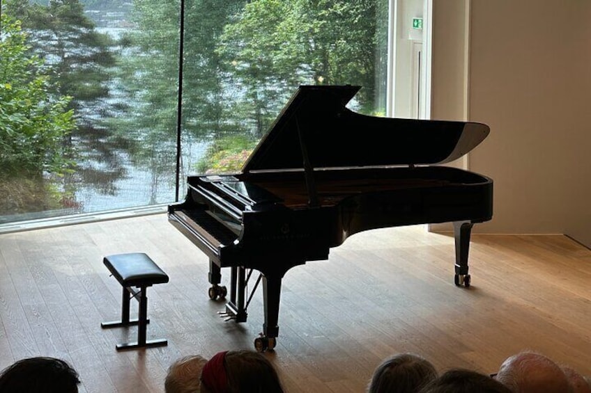 A grand piano in a room with a large window overlooking a lake. 2