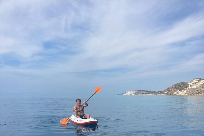 A person kayaking on calm water with a clear sky and distant landforms. 5